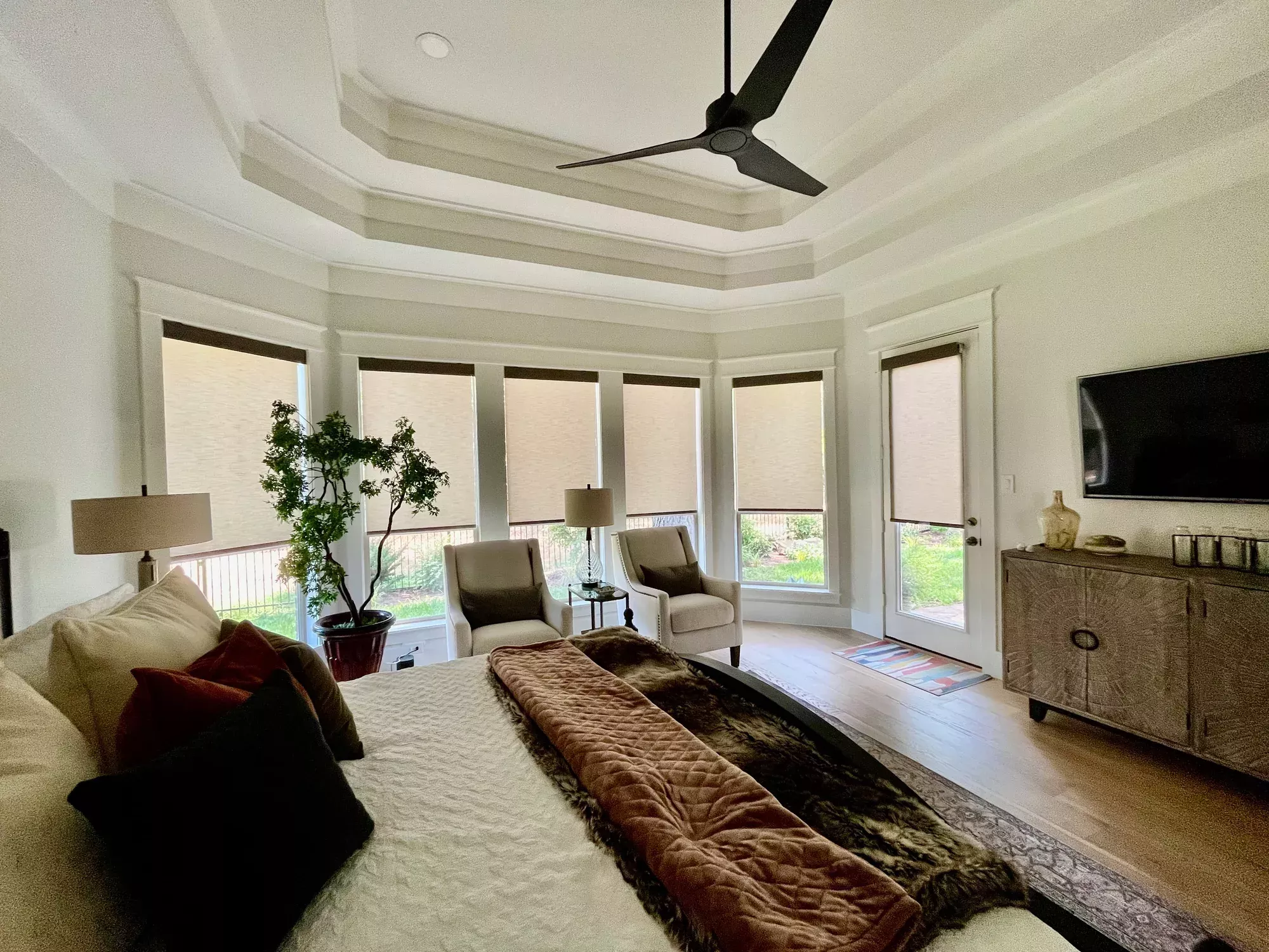 Image shows a bedroom with six windows with blinds open half way.